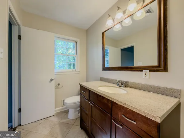 a bathroom with a granite countertop sink a large mirror and a toilet