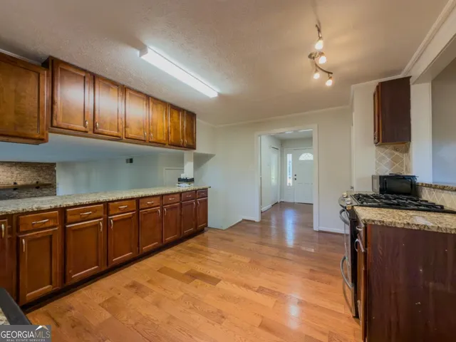 a kitchen with stainless steel appliances granite countertop wooden cabinets a stove top oven a sink and dishwasher
