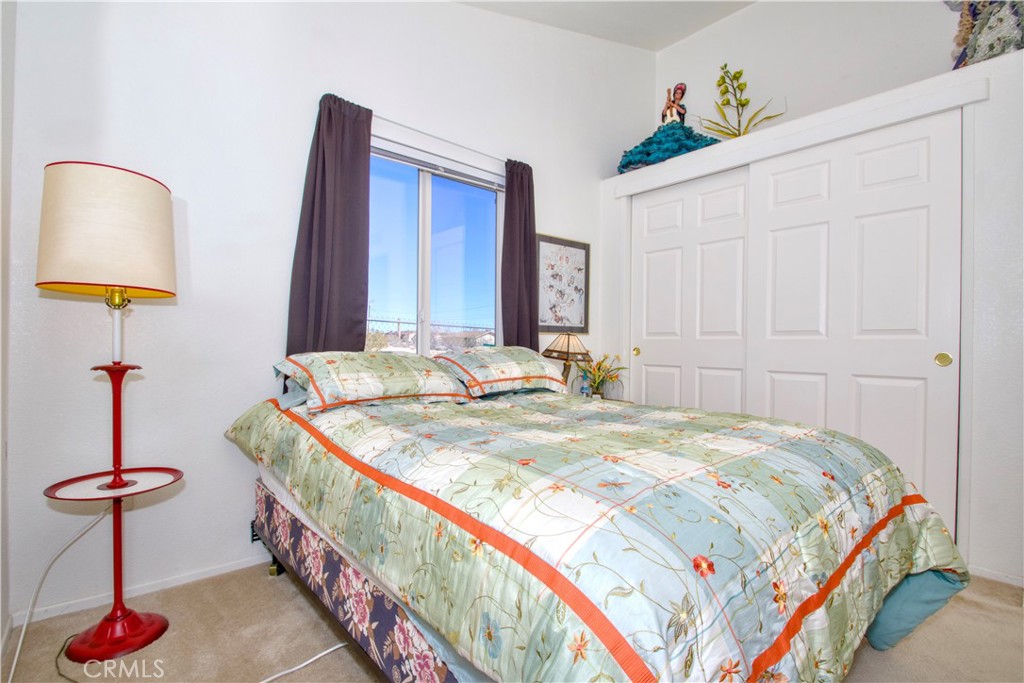 4742 Avenida La Mirada Joshua Tree, CA 92252 - Photo 20 of 45 a bedroom with bed and a chandelier