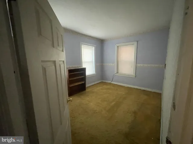 a view of an empty room with closet and a window