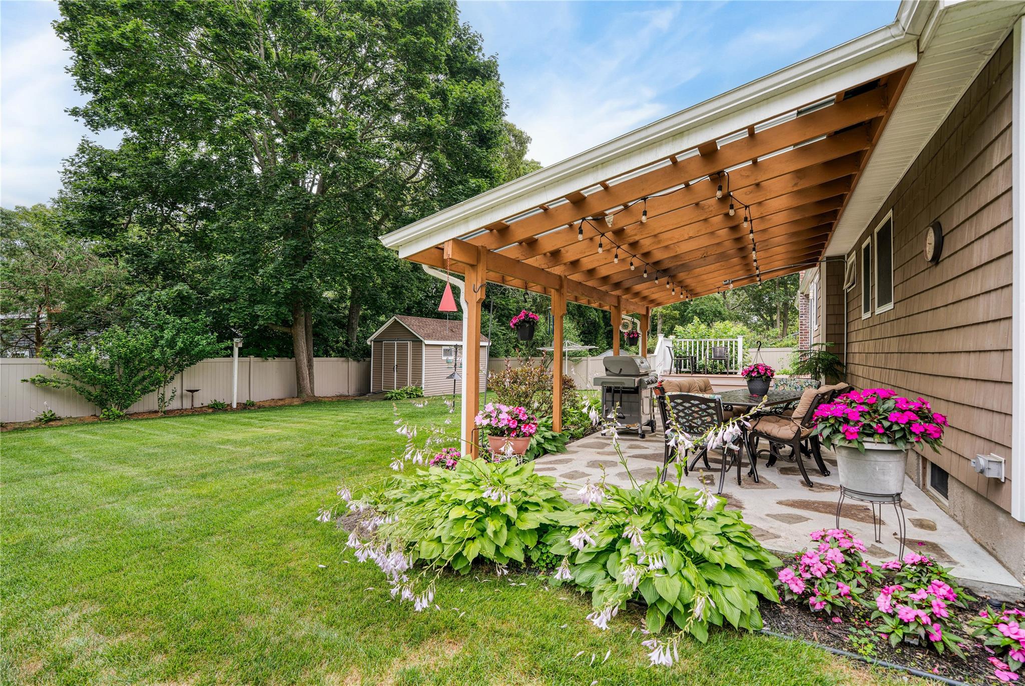7 Russell Road Hampton Bays, NY 11946 - Photo 20 of 31 Fenced backyard with a shed, a patio, a pergola, and outdoor dining space