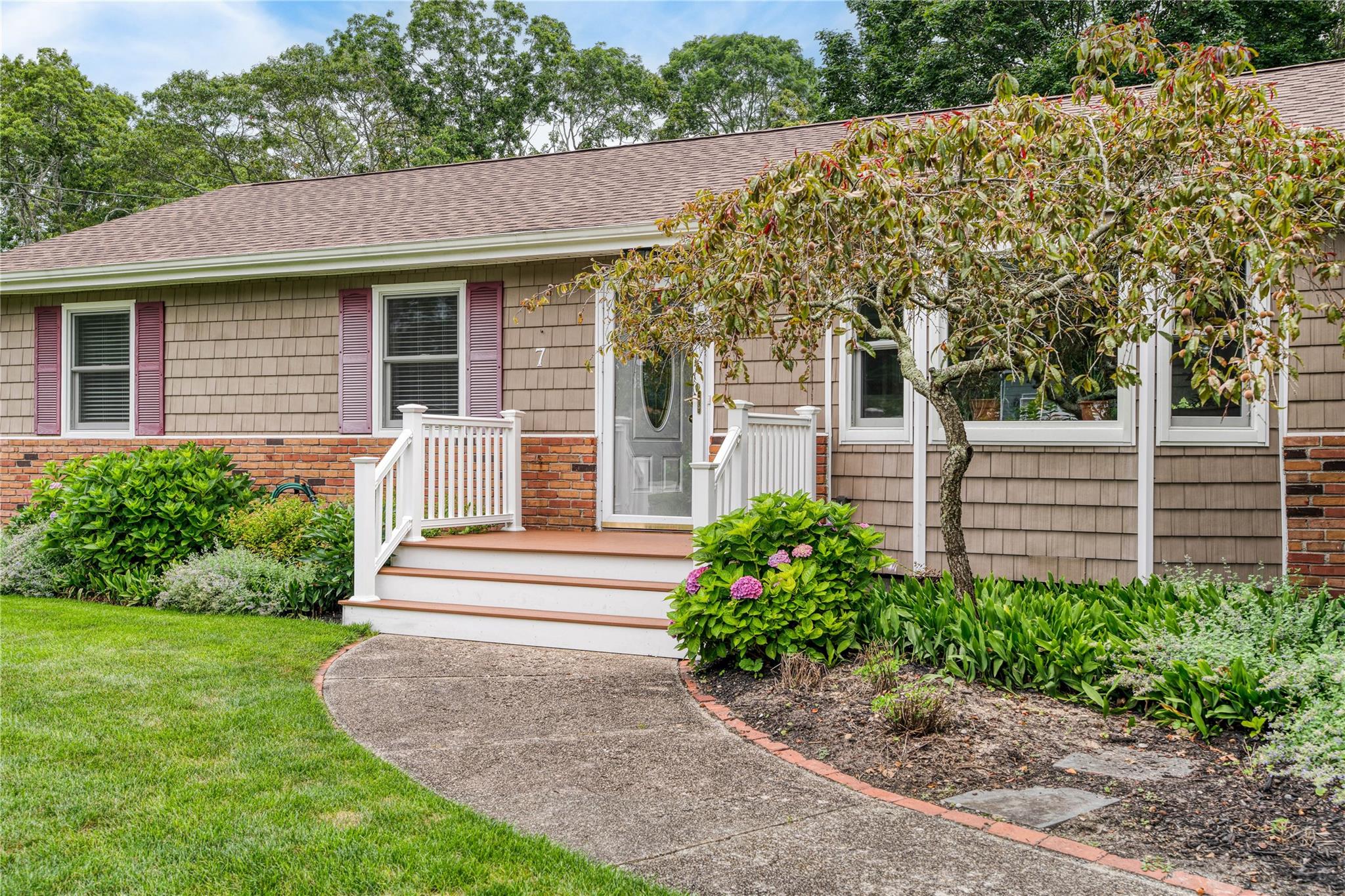 7 Russell Road Hampton Bays, NY 11946 - Photo 2 of 31 View of front of house with roof with shingles, a front yard, and brick siding