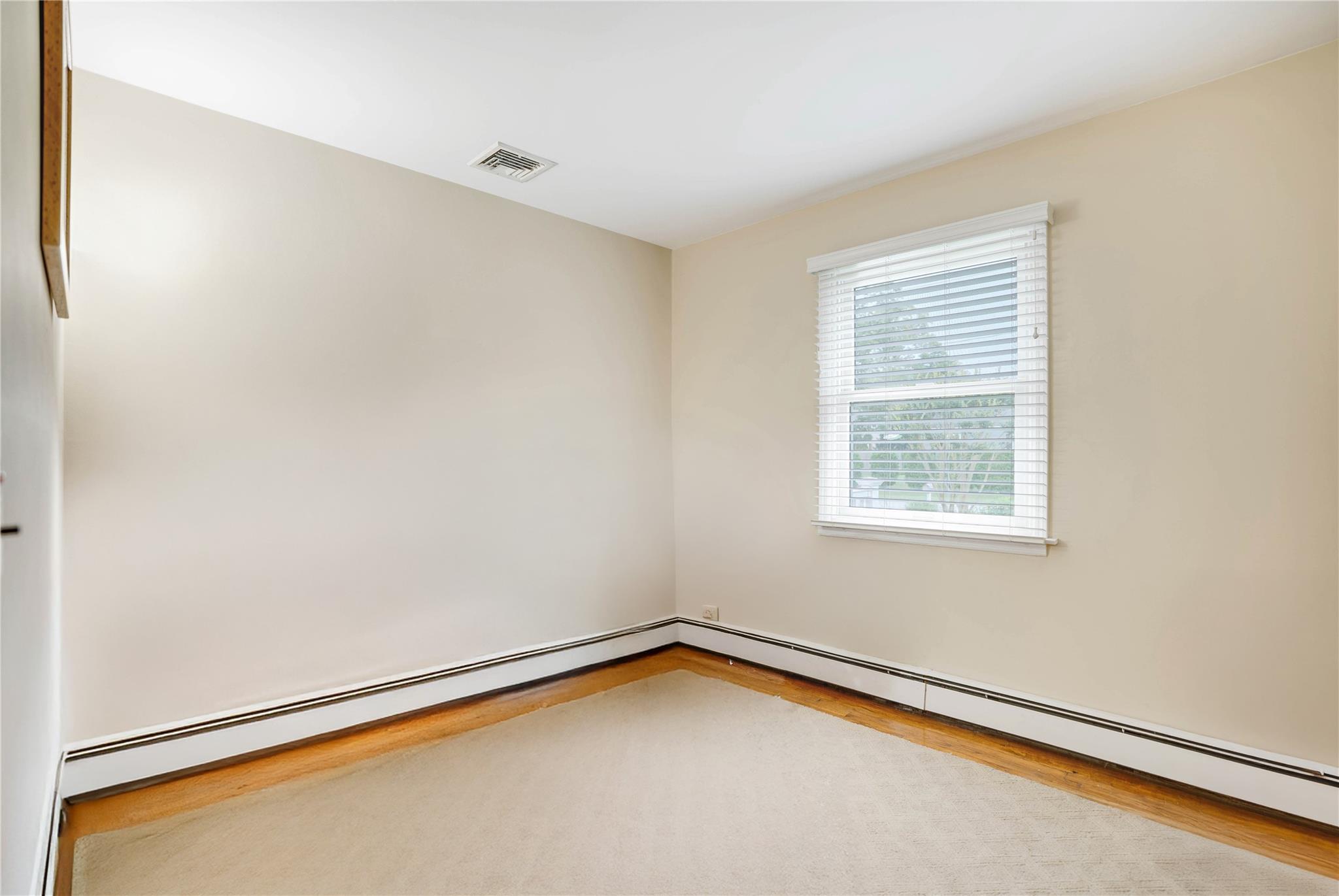 7 Russell Road Hampton Bays, NY 11946 - Photo 25 of 31 Empty room featuring a baseboard radiator and wood finished floors
