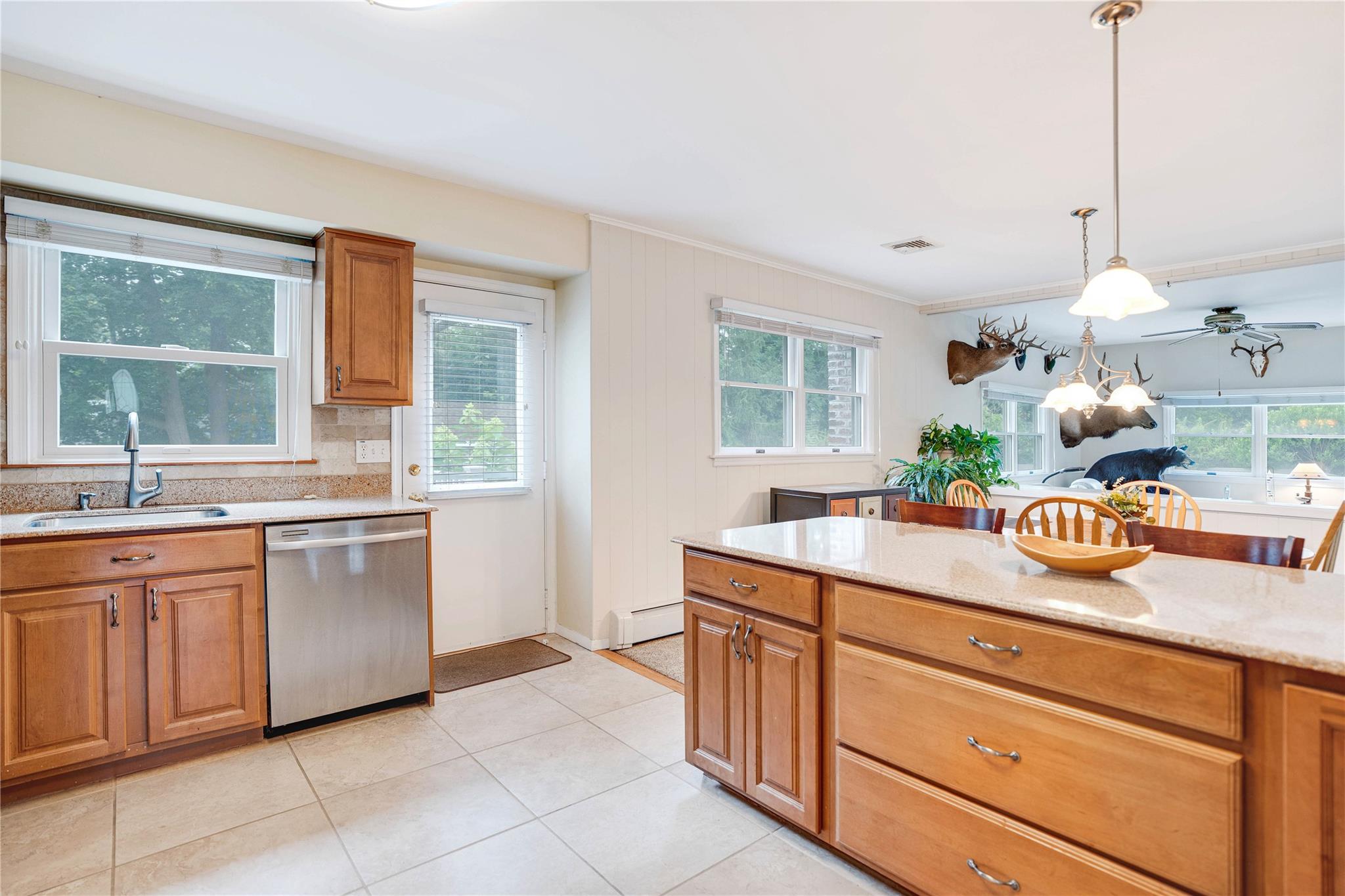 7 Russell Road Hampton Bays, NY 11946 - Photo 27 of 31 Kitchen with stainless steel dishwasher, plenty of natural light, brown cabinets, and crown molding