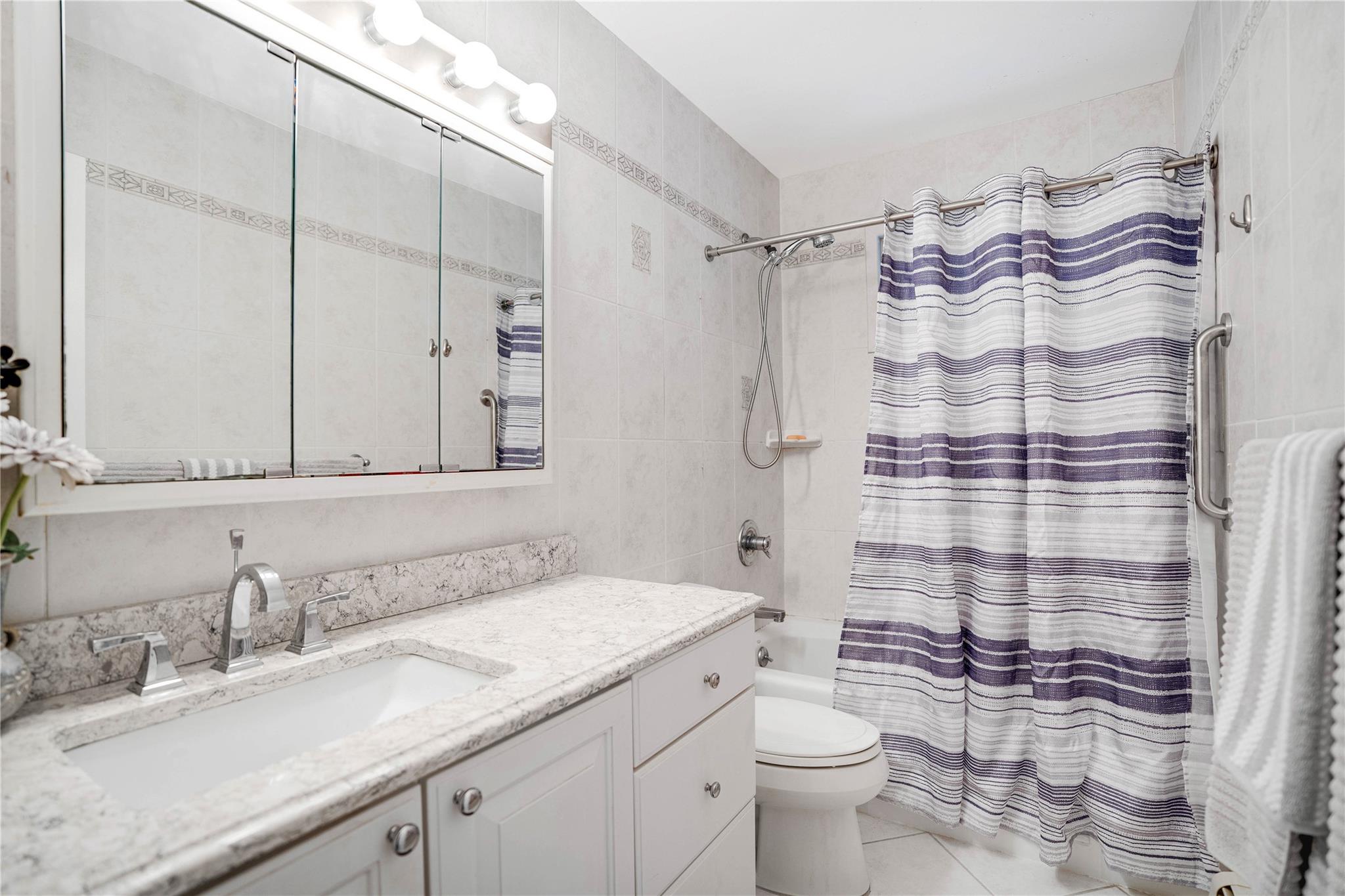 7 Russell Road Hampton Bays, NY 11946 - Photo 5 of 31 Full bath with vanity, shower / bathtub combination with curtain, tile patterned flooring, and tile walls