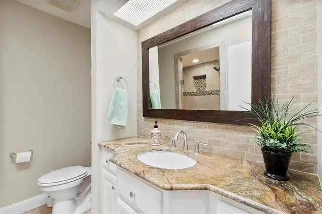 a bathroom with a granite countertop sink a toilet and a mirror