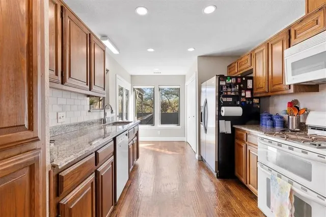 a kitchen with stainless steel appliances granite countertop a lot of counter space and wooden floors