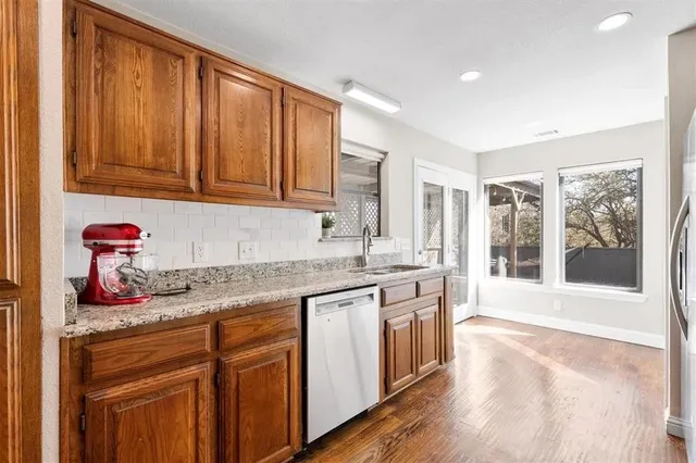 a kitchen with granite countertop stainless steel appliances a sink stove and cabinets