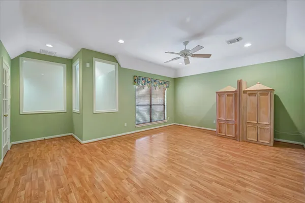 a view of empty room with wooden floor and fan