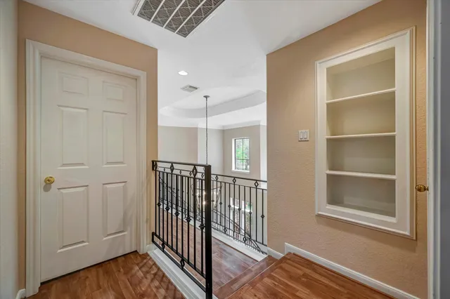 a view of a hallway with wooden floor and a bathroom