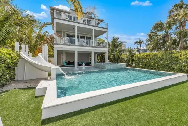 a large white kitchen with kitchen island a large counter top space a sink stainless steel appliances and cabinets
