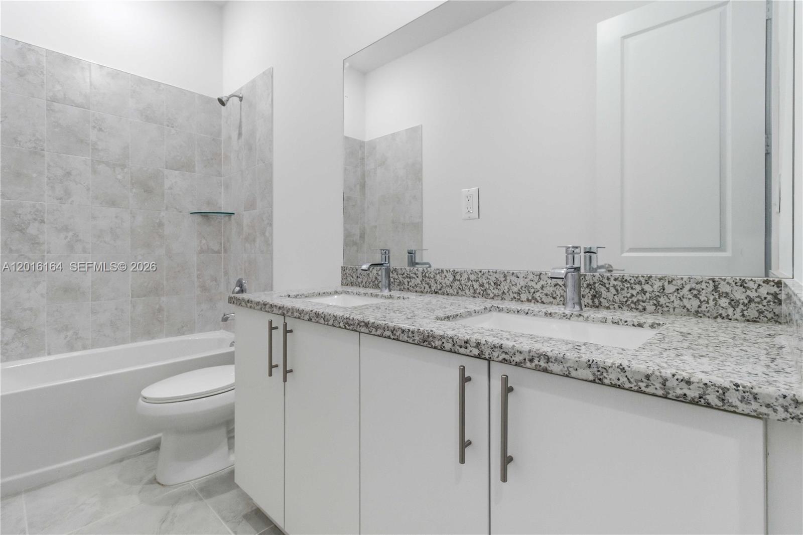 18901 Southwest 316th Street Homestead, FL 33030 - Photo 28 of 33 a bathroom with a granite countertop sink a toilet and a bathtub