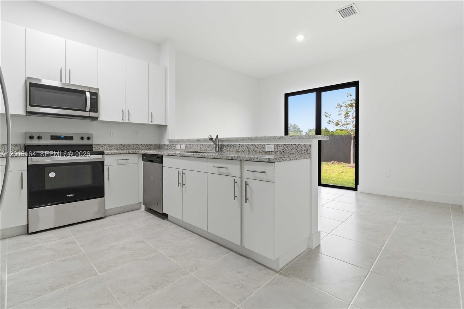 18901 Southwest 316th Street Homestead, FL 33030 - Photo 9 of 33 a kitchen with stainless steel appliances granite countertop a stove a sink and a microwave