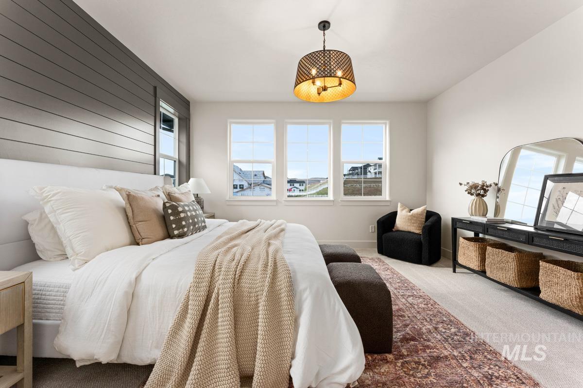 13338 North Spring Creek Way Boise, ID 83714 - Photo 18 of 46 Bedroom featuring a shiplap accent wall, three large windows, a sophisticated ceiling fixture, neutral carpet, and a dedicated sitting area