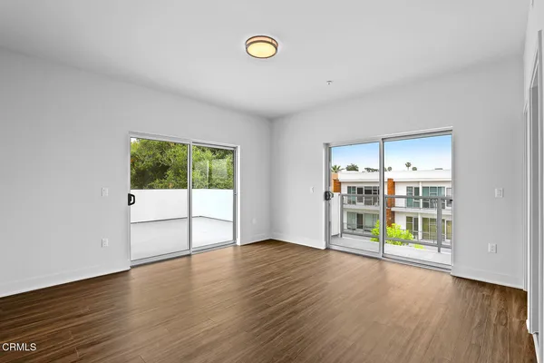 a view of an empty room with window and wooden floor