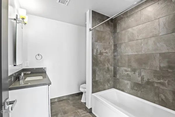 a bathroom with a granite countertop sink a toilet and shower