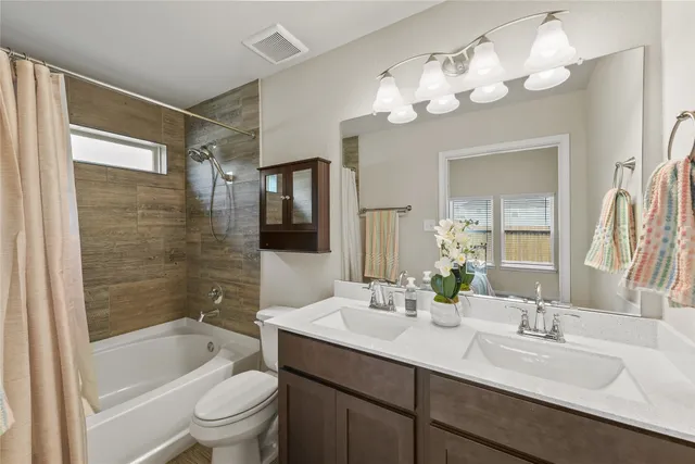 a bathroom with a granite countertop sink a toilet a mirror a bathtub and shower