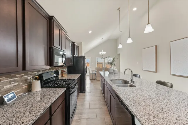 a kitchen with granite countertop a sink a counter top space and cabinets