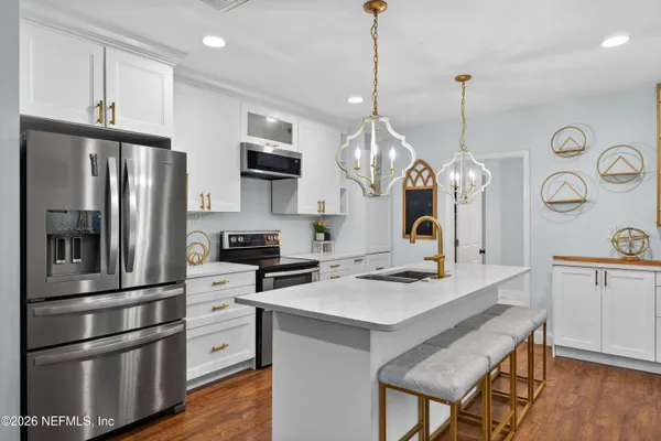 a kitchen with stainless steel appliances granite countertop a refrigerator a stove a sink dishwasher a oven a dining table and chairs with wooden floor