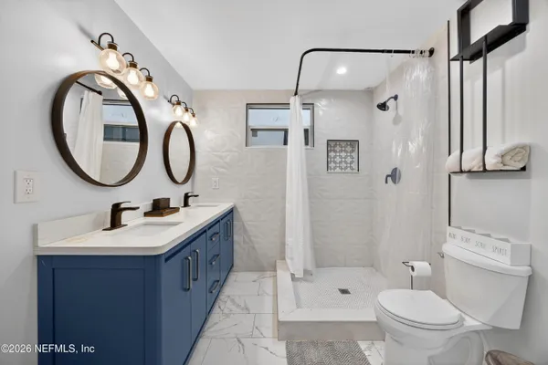 a bathroom with a double vanity sink toilet mirror and shower