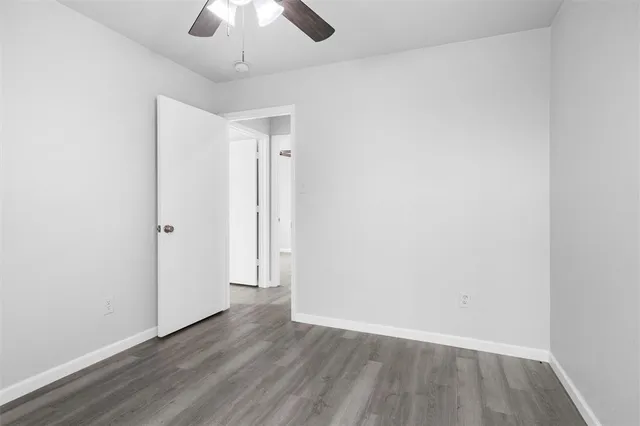 an empty room with wooden floor and chandelier fan