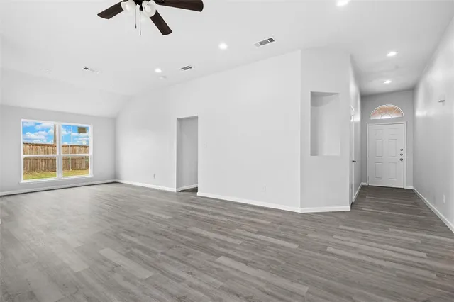 an empty room with wooden floor and windows