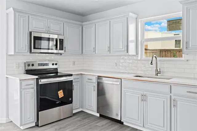 a kitchen with white cabinets stainless steel appliances and sink