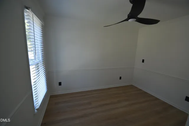 an empty room with wooden floor cabinet and windows