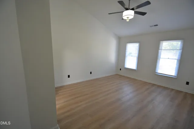 a view of empty room with wooden floor and fan