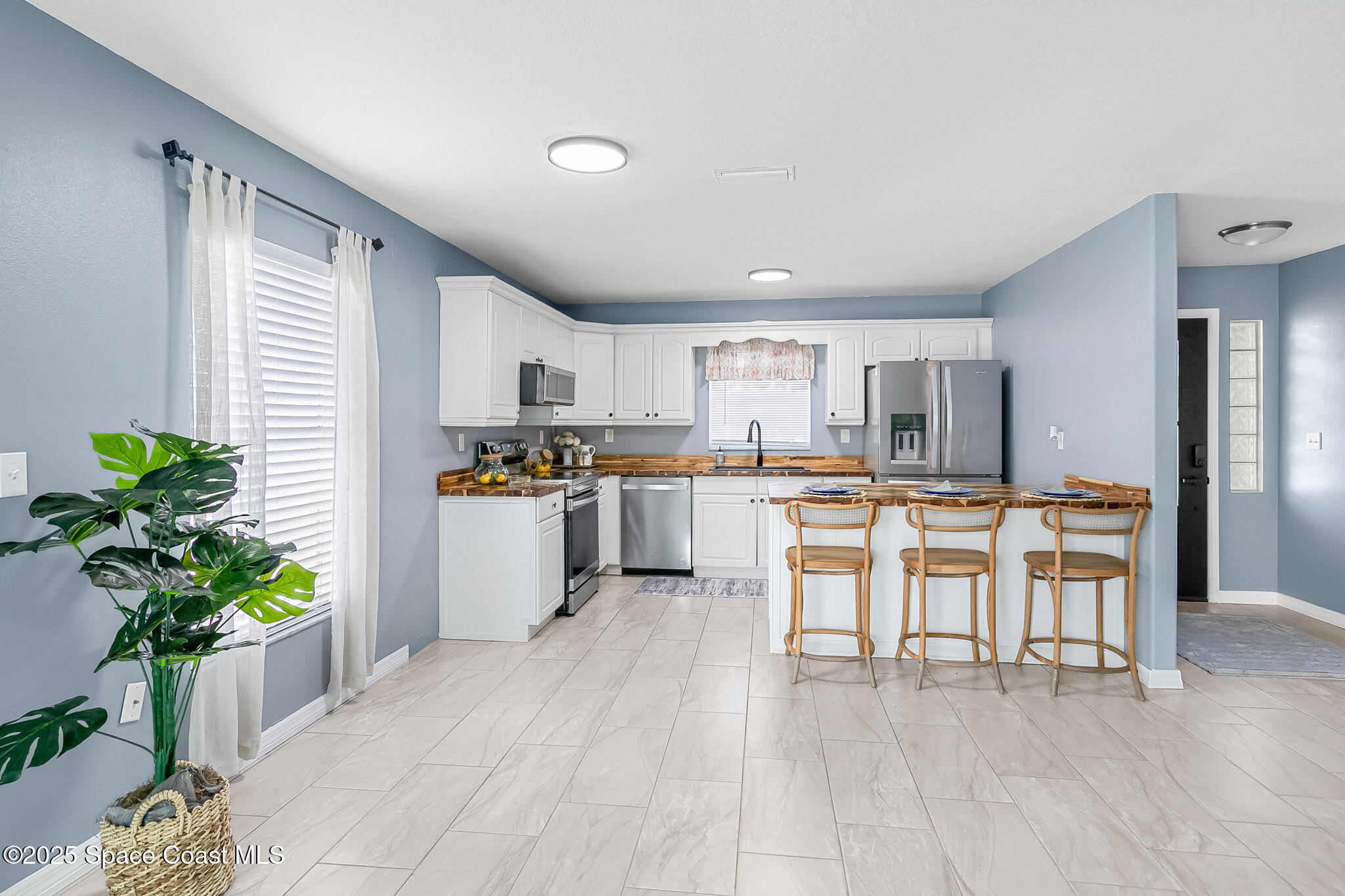 233 Broadview Drive Cocoa, FL 32922 - Photo 12 of 44 a kitchen with stainless steel appliances kitchen island granite countertop a refrigerator a stove a sink dishwasher and white cabinets with wooden floor