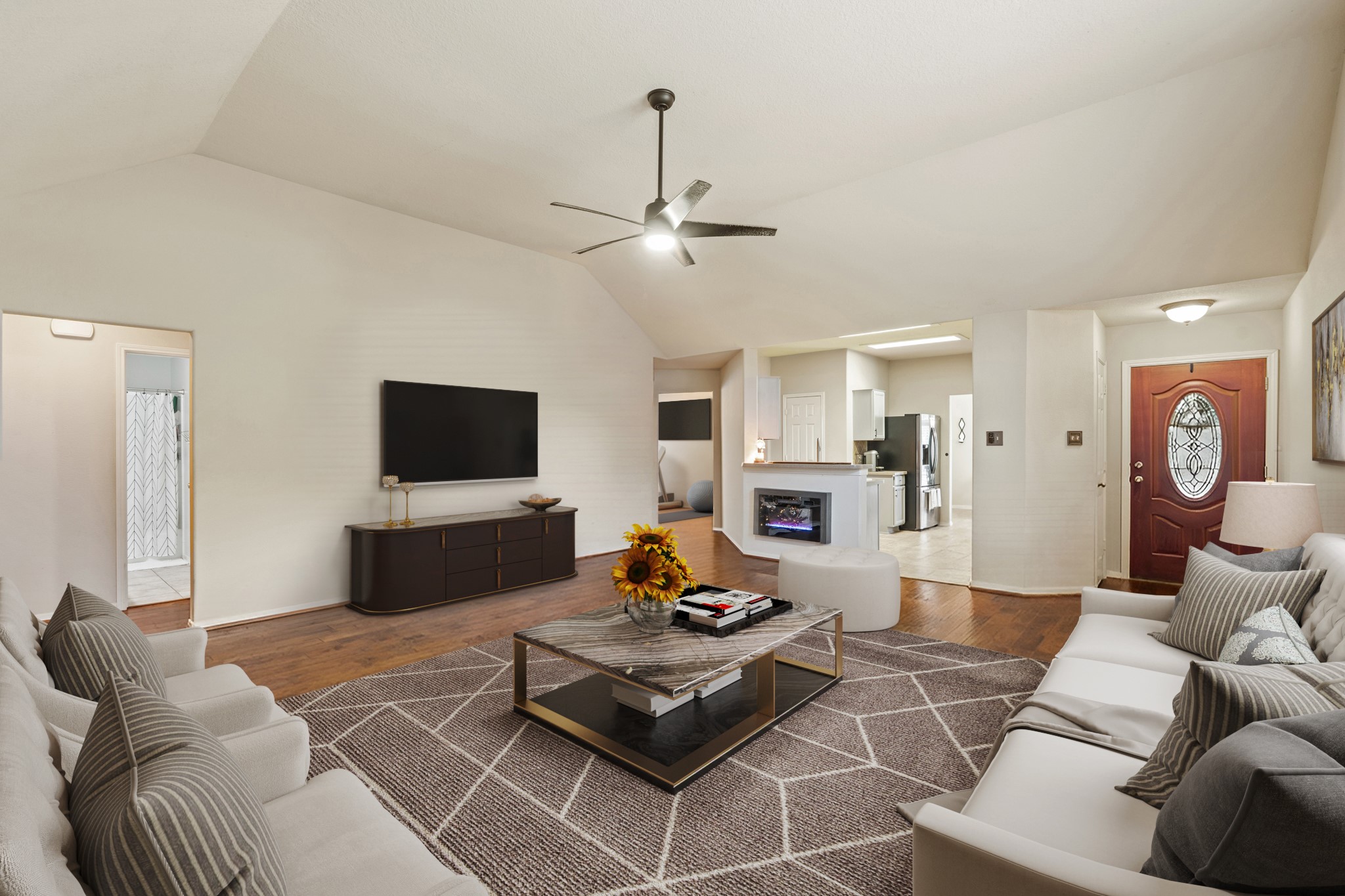 19646 Hardwood Ridge Trail Cypress, TX 77429 - Photo 4 of 22 Virtually Staged: This living room is spacious and inviting, designed for both comfort and entertaining. It features vaulted ceilings that create an open, airy feel, paired with rich hardwood flooring that adds warmth and character to the space. A modern ceiling fan provides both style and airflow, enhancing everyday comfort.