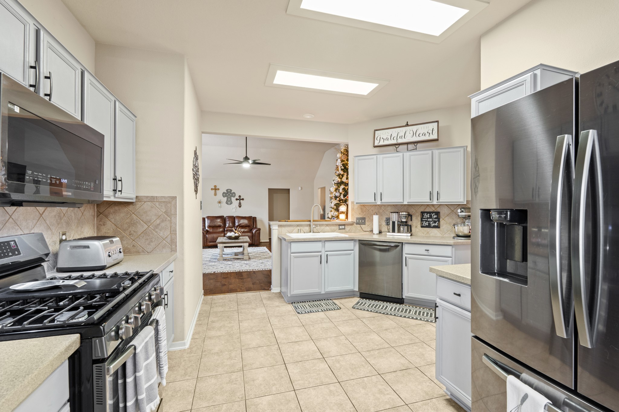 19646 Hardwood Ridge Trail Cypress, TX 77429 - Photo 8 of 22 Surrounding cabinetry offers ample storage, complemented by stainless steel appliances, including a refrigerator and range. Overhead skylights fill the room with natural light, creating an airy atmosphere throughout the day.