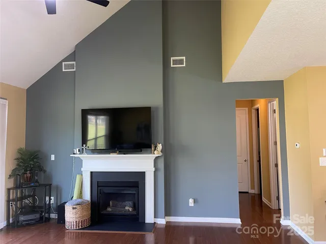 a living room with a fireplace a flat screen tv and a potted plant