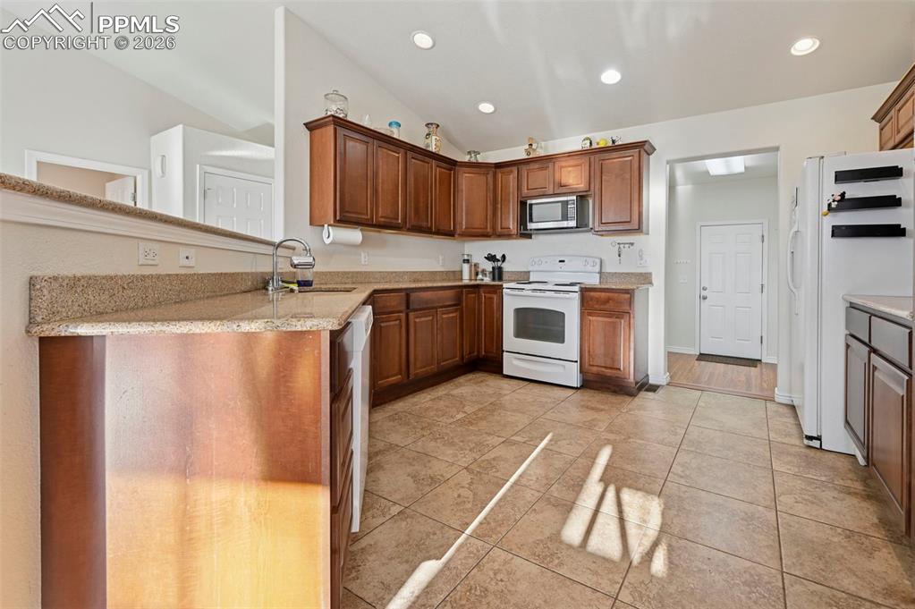 16575 Cathys Loop Peyton, CO 80831 - Photo 12 of 49 a large kitchen with stainless steel appliances granite countertop a stove a sink and a refrigerator