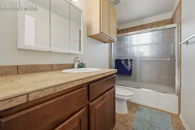 a bathroom with a granite countertop sink a toilet and shower