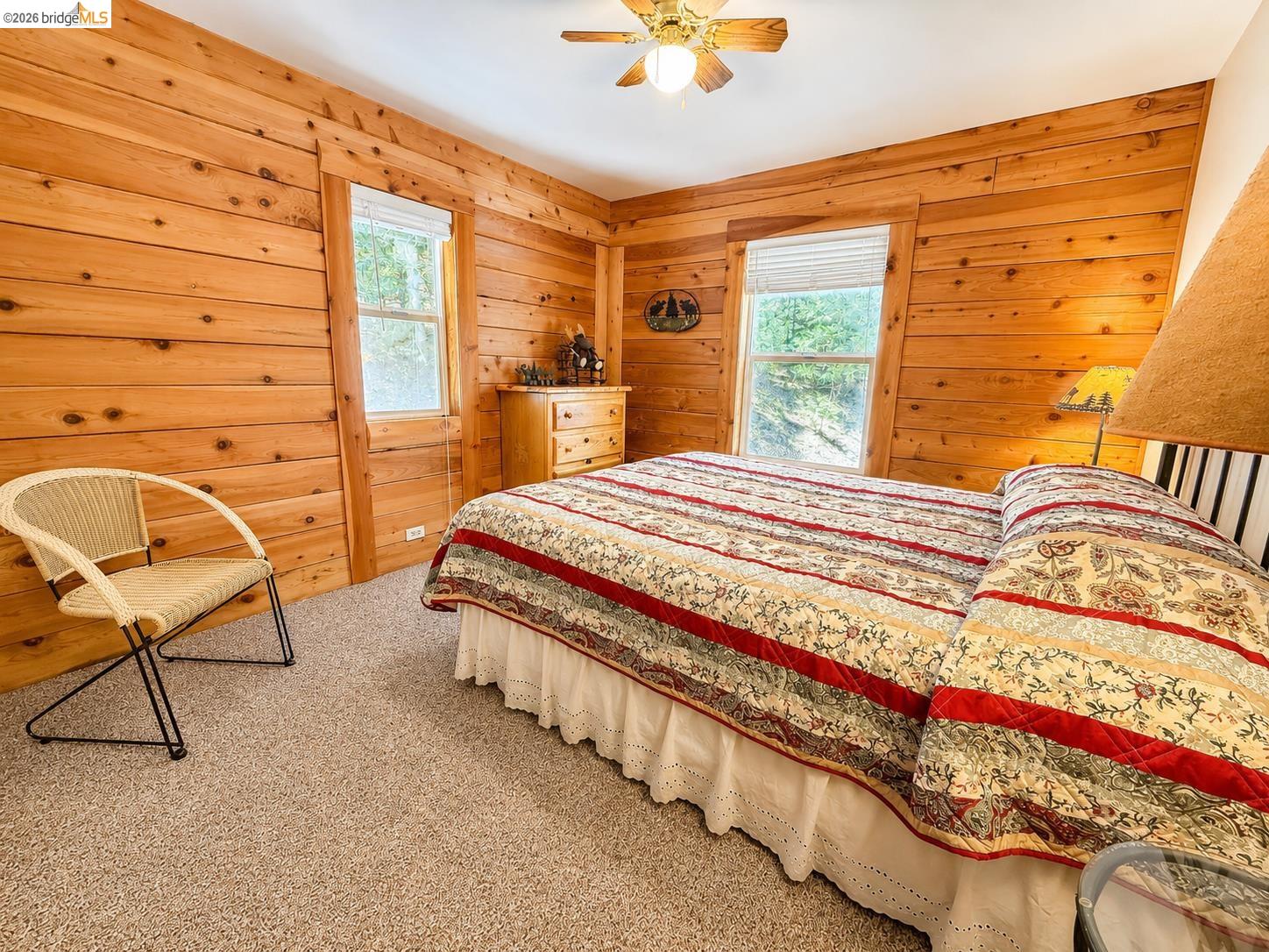 21181 Phoenix Lake Road Sonora, CA 95370 - Photo 28 of 34 Room featuring natural wood-paneled walls, two windows with white blinds, and a built-in ceiling fan with a light fixture