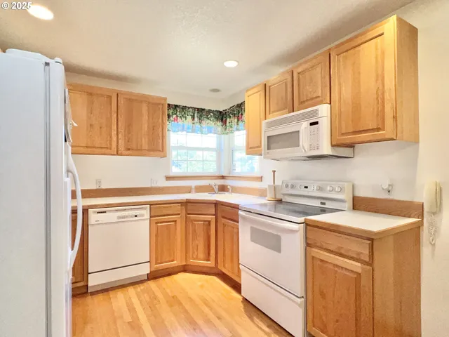 a kitchen with stainless steel appliances granite countertop a sink stove and white cabinets with wooden floor