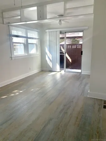 an empty room with wooden floor fireplace and windows