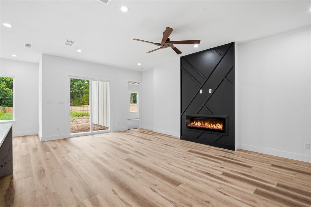 1111 Riverwood Road Dallas, TX 75217 - Photo 20 of 40 Living area featuring a modern electric fireplace with a black accent wall, wood-finish flooring, a ceiling fan, recessed lighting, and a sliding glass door to the exterior
