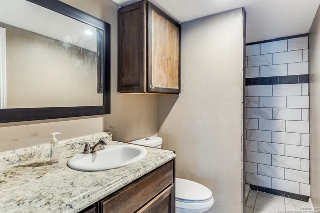 a bathroom with a granite countertop sink toilet and mirror