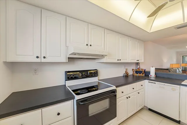 a kitchen with granite countertop white cabinets and white appliances