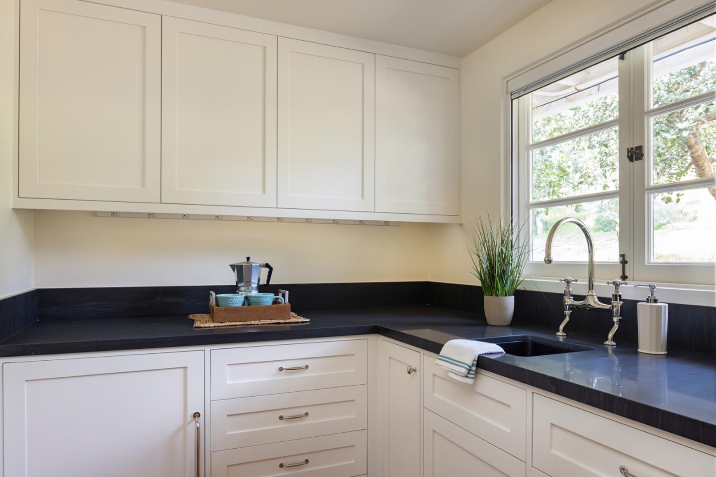 3269 Cabrillo Road Pebble Beach, CA 93953 - Photo 40 of 44 a kitchen with granite countertop white cabinets white appliances a sink and large window