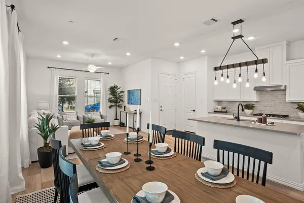 a open dining room with furniture a chandelier and wooden floor