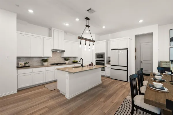 a kitchen with a refrigerator a white cabinets and chairs
