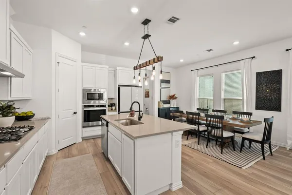 a kitchen with a refrigerator a stove a sink dishwasher with a dining table and chairs