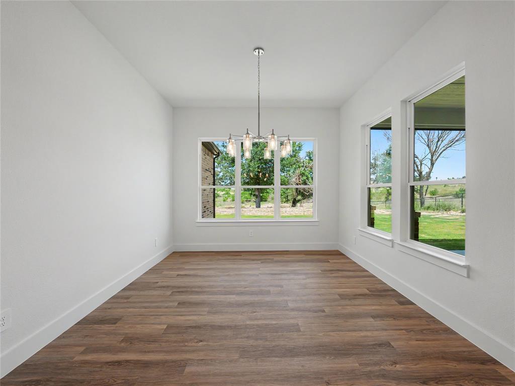 328 Slimp Bluff Azle, TX 76020 - Photo 12 of 30 Spacious room featuring wood-finish flooring, white baseboards, and a contemporary chandelier