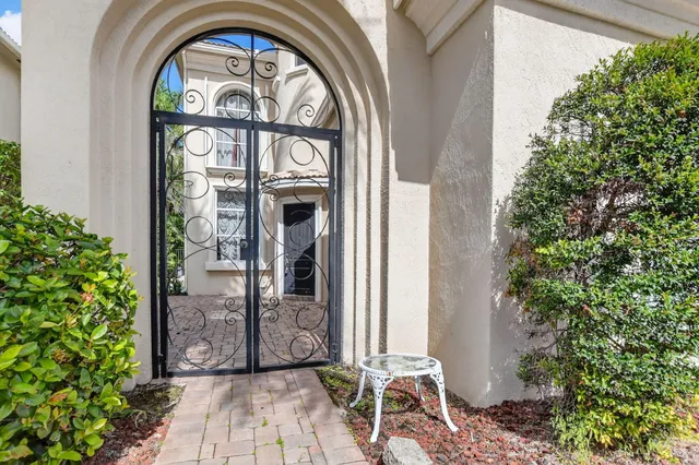a view of a brick house with potted plants and a large tree
