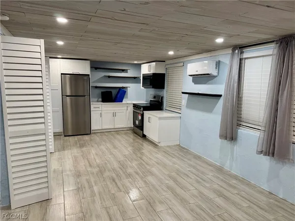 a living room with stainless steel appliances furniture a refrigerator and a kitchen stove