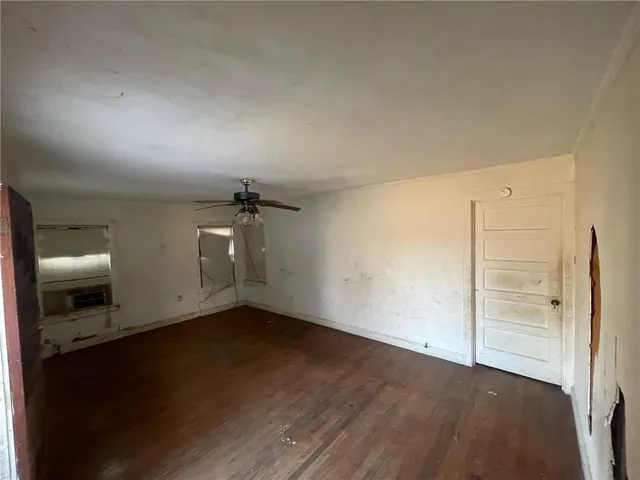 an empty room with wooden floor cabinet and windows
