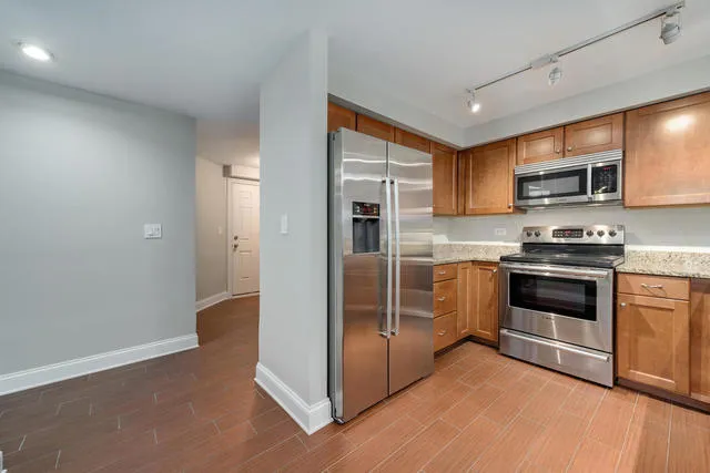a kitchen with granite countertop a refrigerator and a stove top oven